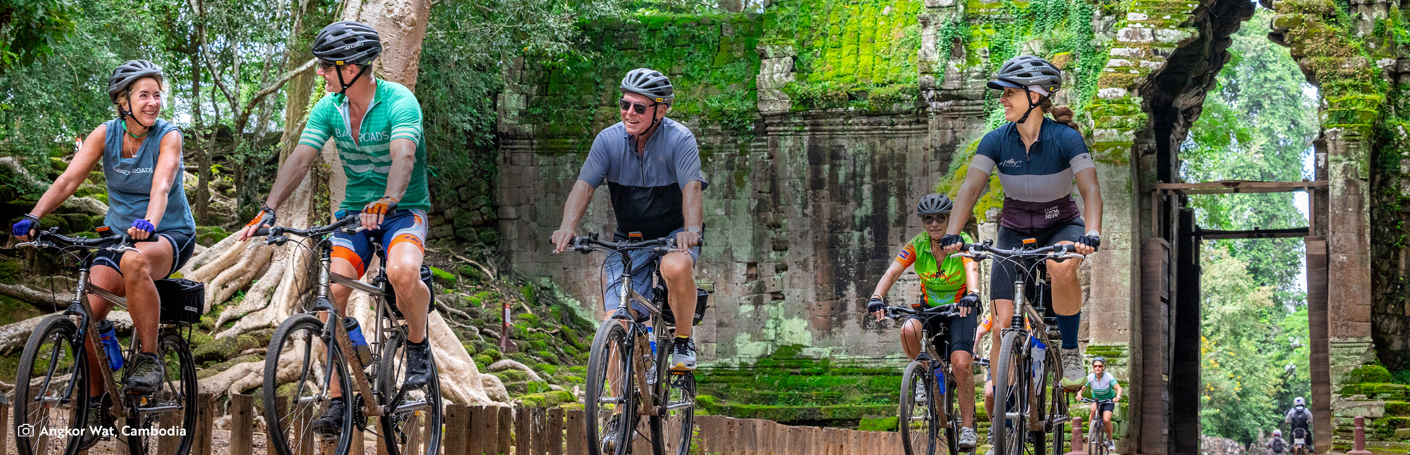 Backroads guests biking through a stone gate