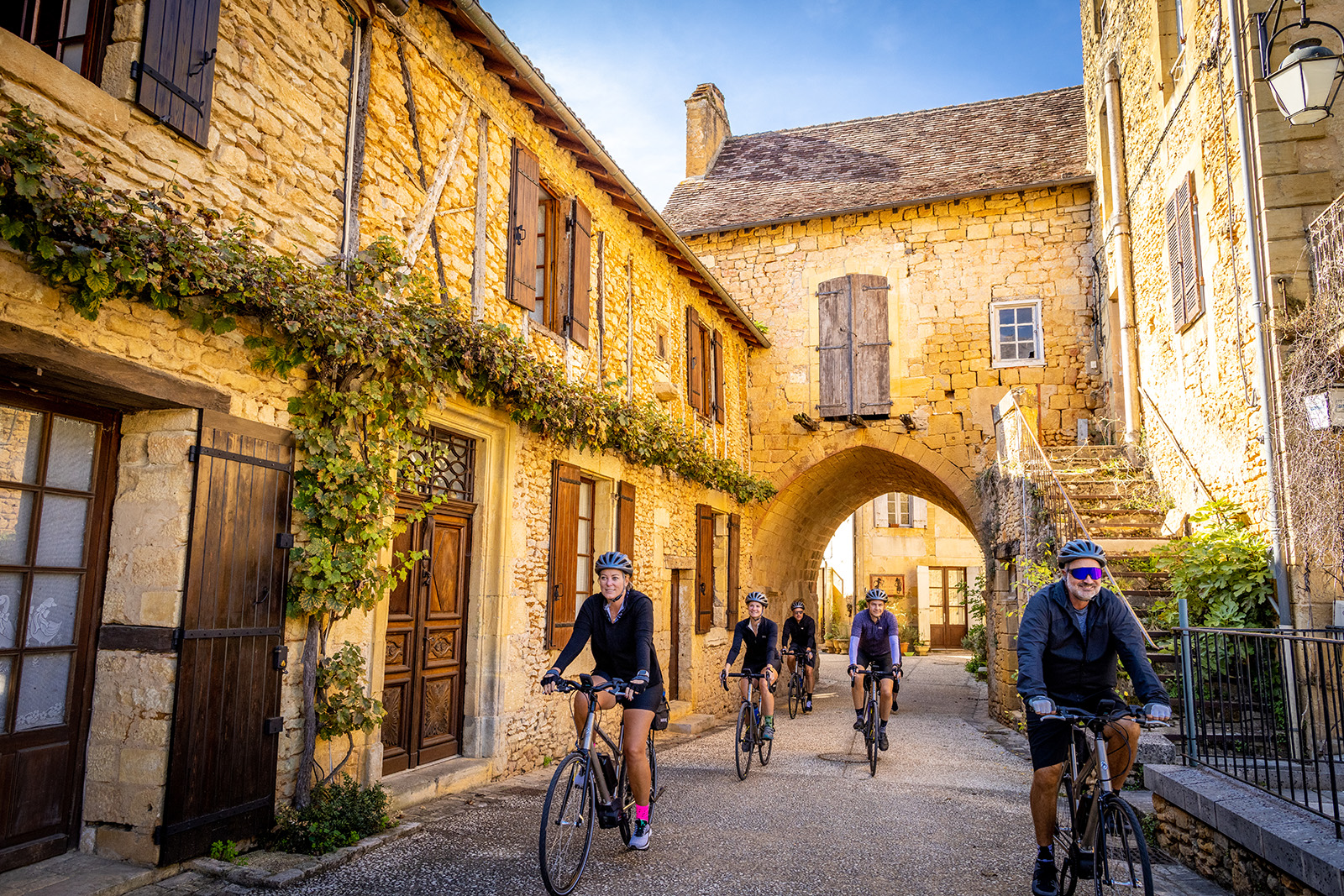 Bikers going through a town of stone buildings