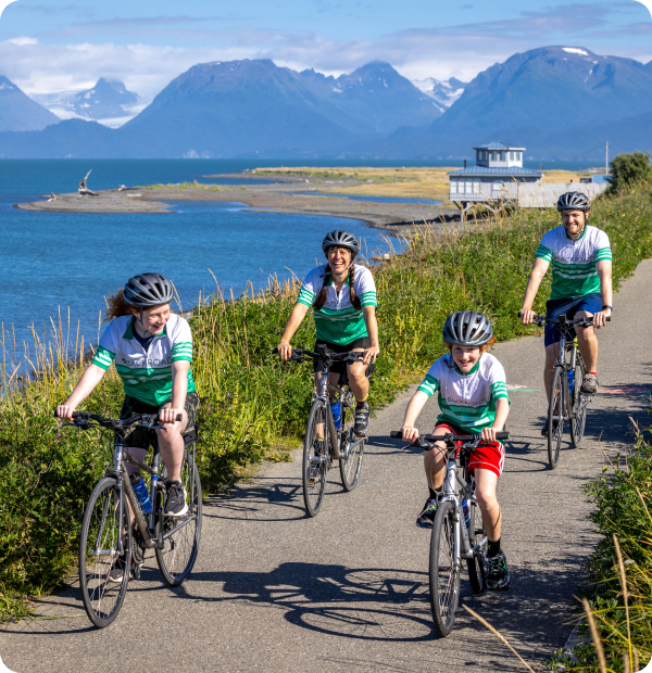 Family riding bikes along a bay in Alaska