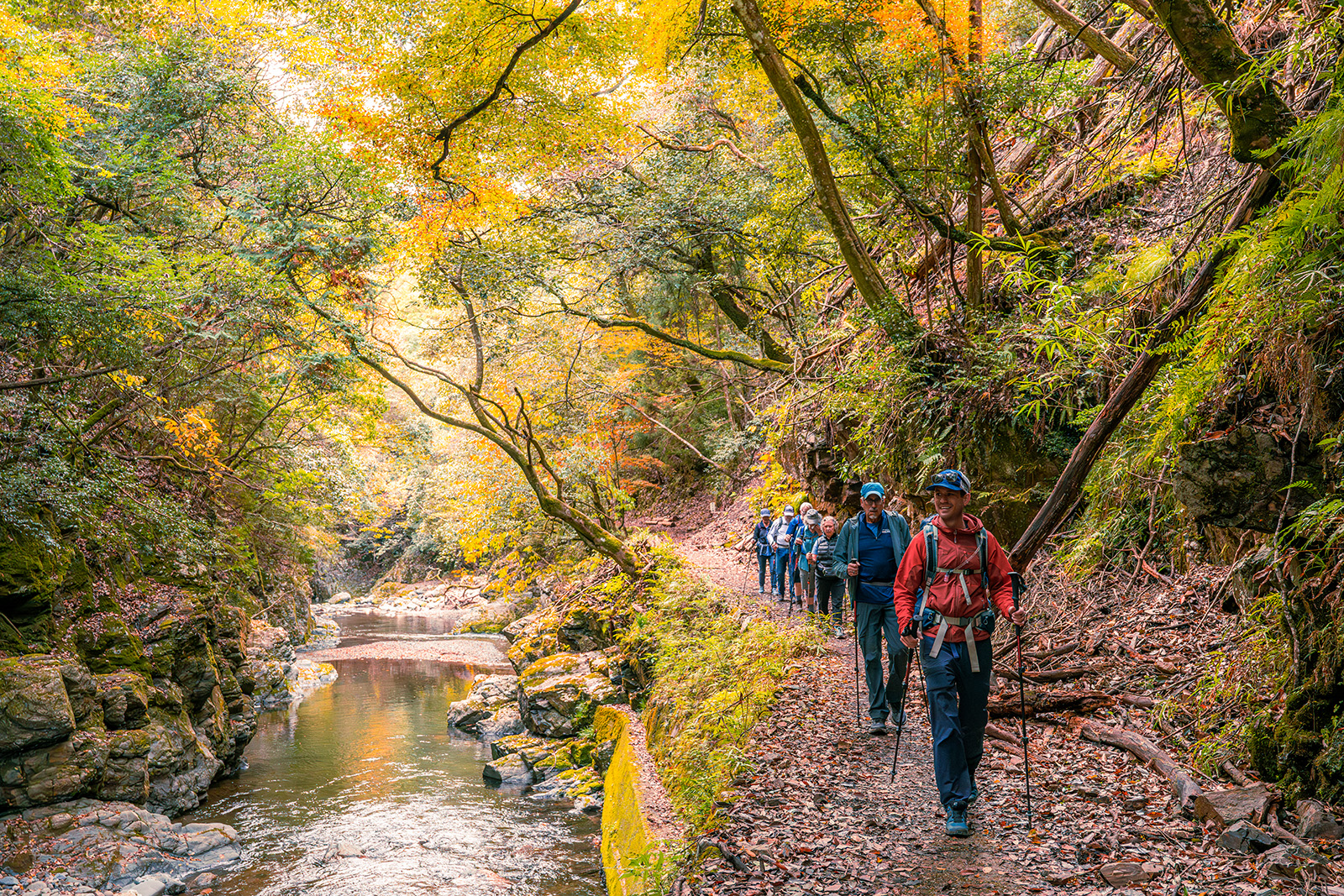 A line of hikers pass by a river