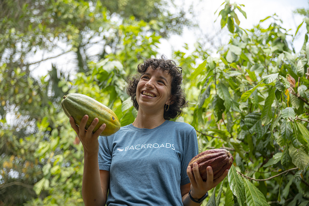 Woman standing in the middle of a forest holding up two large fruits