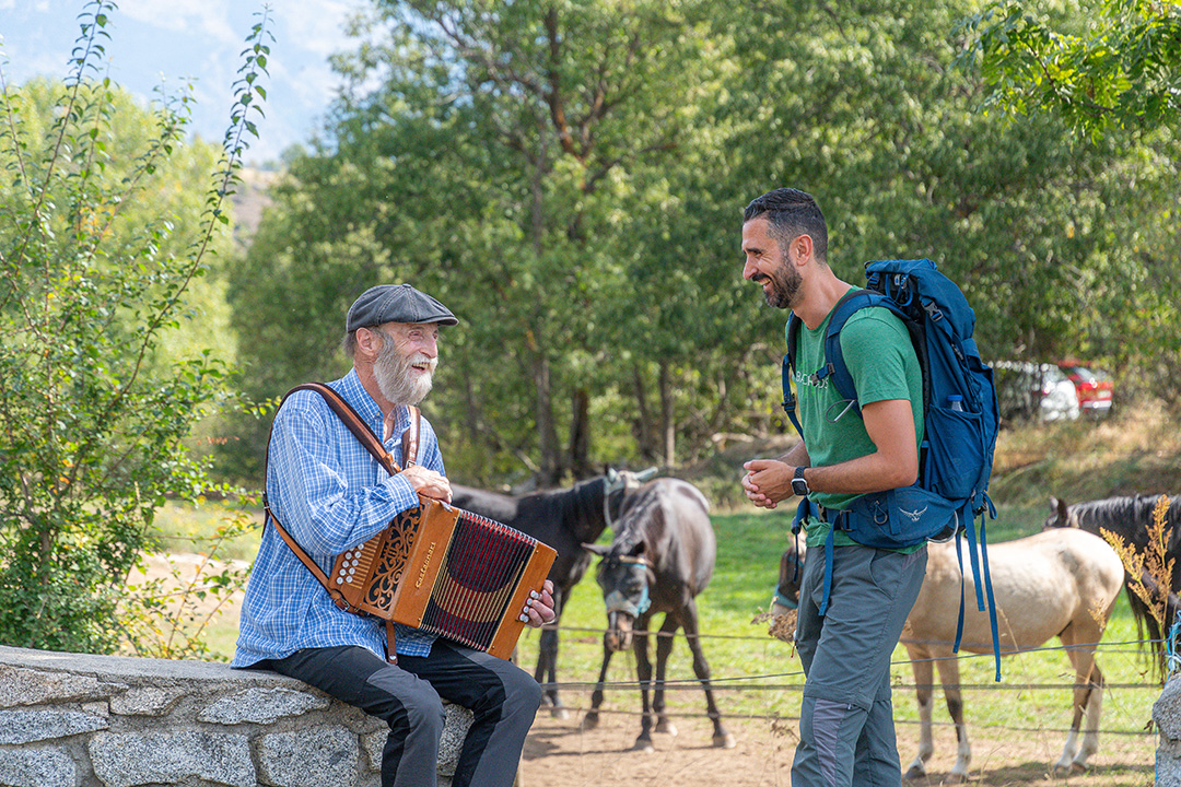 Man playing an accordion with another man smiling, looking at him