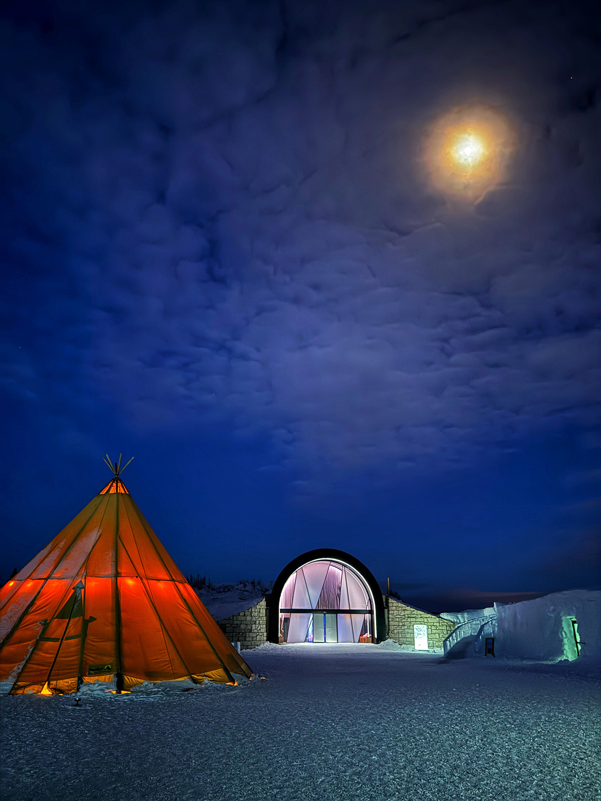 Lit up tents under blue sky and moon