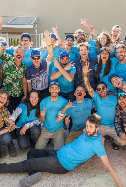 Group of people in blue t-shirts lifting their arms and smiling