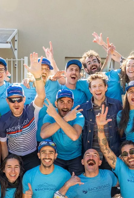 Group of people wearing Backroads shirts with their arms open while smiling