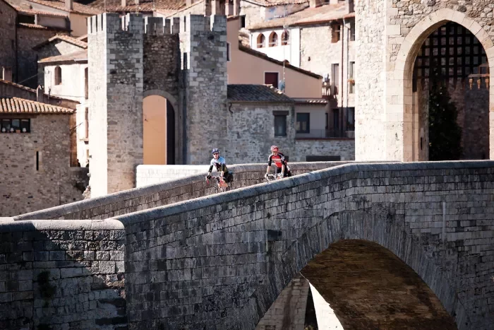Two bikers on a stone bridge in a town