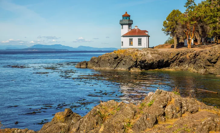 Coastal shot of a small lighthouse on a rocky shore.