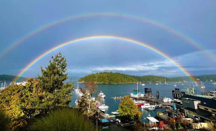 Wide shot of coastal port town, double rainbow across the sky.