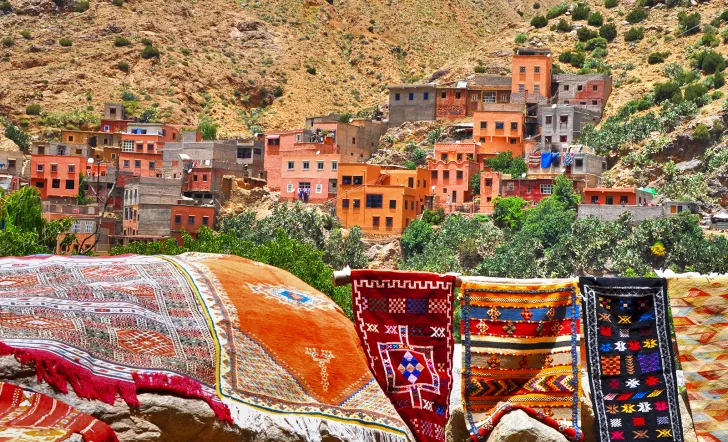 Shot of vibrant desert valley town, tapestries in foreground. 