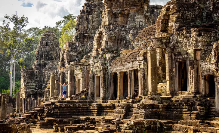 Woman with arms open next to ancient temple ruins