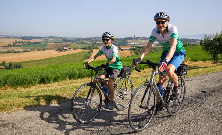 Man and boy biking on a road with fields in the foreground