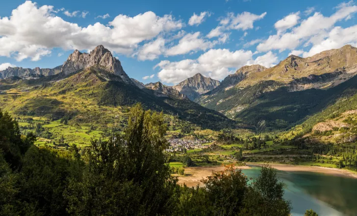 green mountains and lakes below a blue sky with white fluffy clouds