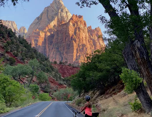 Biker on road looking back towards mountain