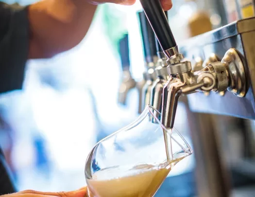 Close-up of a man pouring beer from a tap.