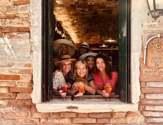 Six guests in window, drinks in hand, smiling at camera.