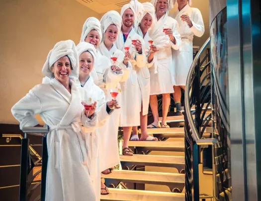Backroads guests lined up in a row on a set of stair, all in white robes and towels on heads.