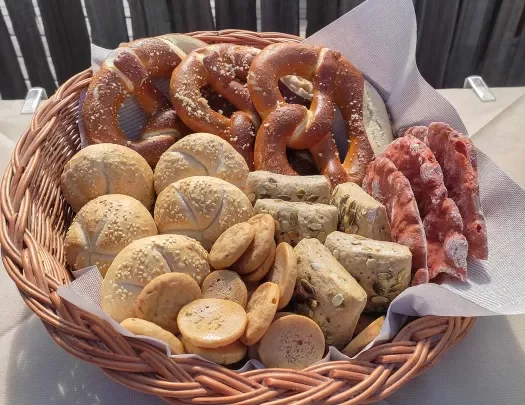 Basket filled with different types of bread and rolls, soft pretzels.