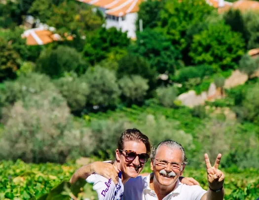 Two people posing in a vineyard.