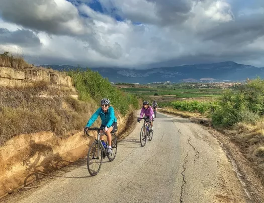 Two bikers cycling on a road in Spain.