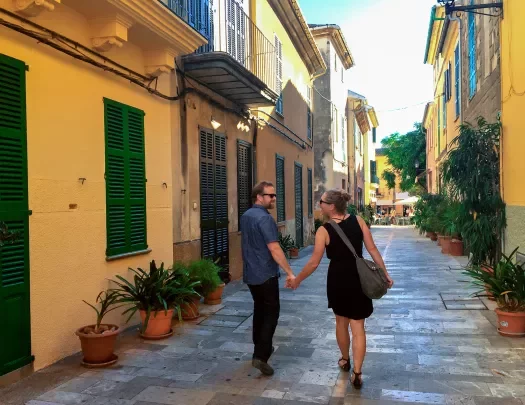 Two guests holding hands walking down an alley way in Mallorca.