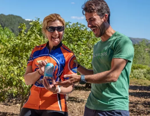 Two bikers posing with a can of wine in a vineyard.