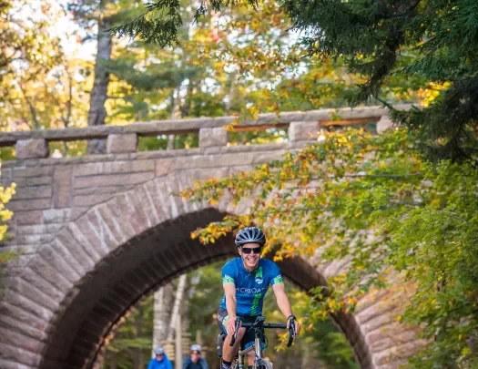 Guests biking under brick bridge.