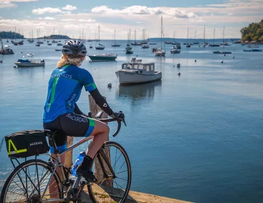 Guest with bike on pier, overlooking bay full of sailboats.