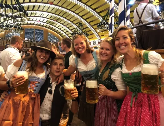 Four people in traditional German dirndels having pints of beer.