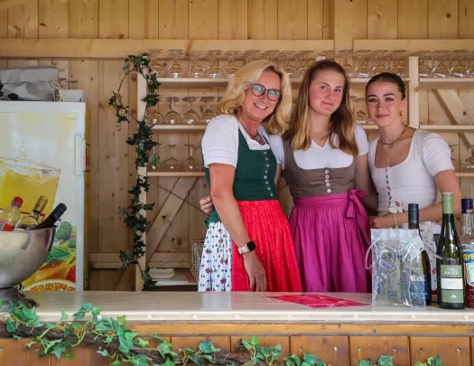 Three women posing together in traditional German dresses.