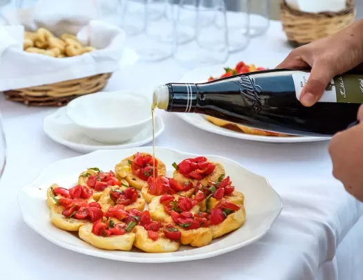 Someone preparing bruschetta, pouring olive oil.