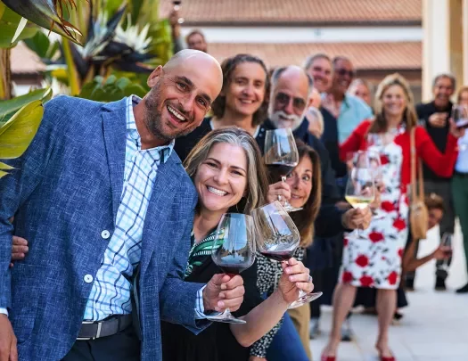 Group of guests, all looking towards camera, wine glasses in hand.