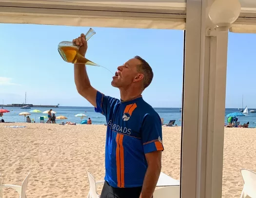 Biker drinking from carafe on the beach.