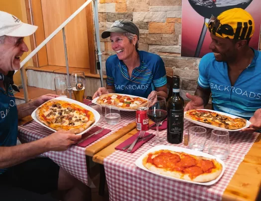 Three guests at lunch, pizzas in hand.