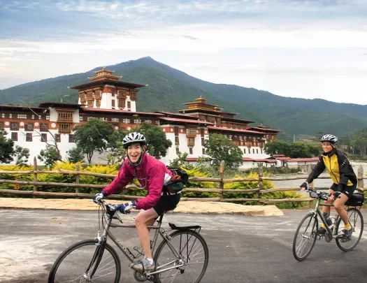 Two bikers riding beside a temple in Bhutan