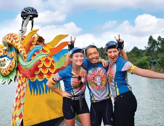 Three Backroads leaders laughing and posing in front of a dragon boat