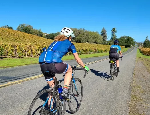 Two guests cycling amidst California vineyards.