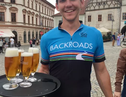 Backroads leader in a bike jersey holding a tray of beers