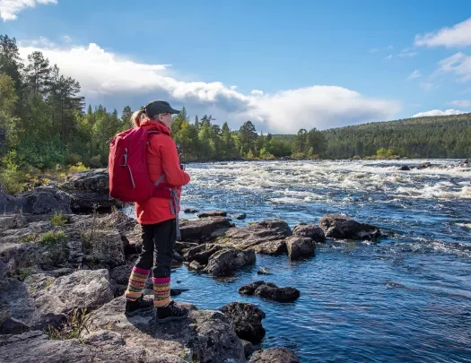 Guest standing next to rough river.