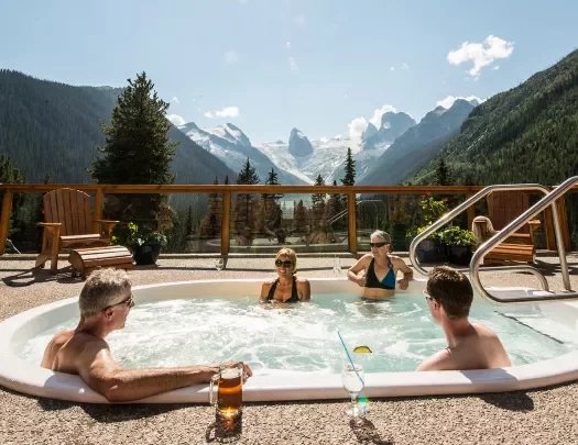 Four guests in hot-tub, mountainous vista behind them.