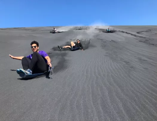 Guests sledding down sand dune