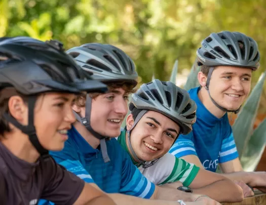 Four young guests in bike gear, talking at table.