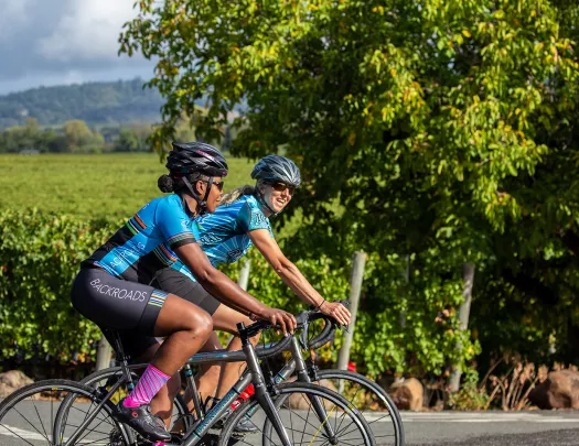 Two guests cycling past vineyard.