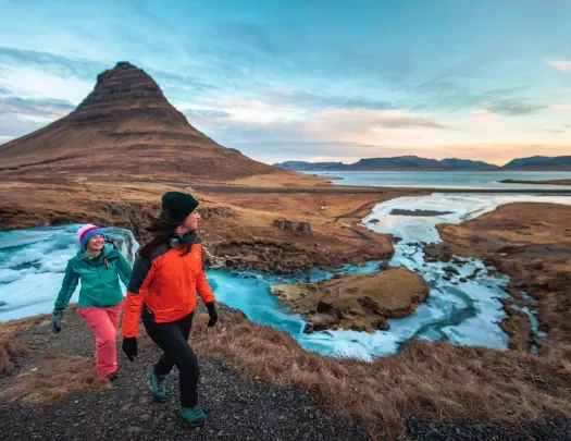 Two hikers walking along side stream of water in Iceland.