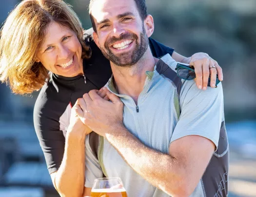 Two guests embracing, one holding glass of beer.