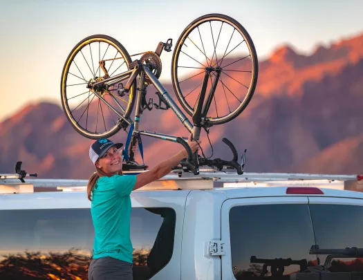 Guide smiling at camera mounting bike on van in arizona