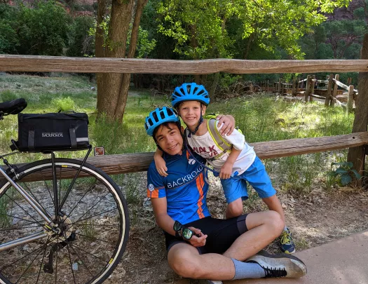 Two young guests in bike gear leaning on fence, bike beside them.