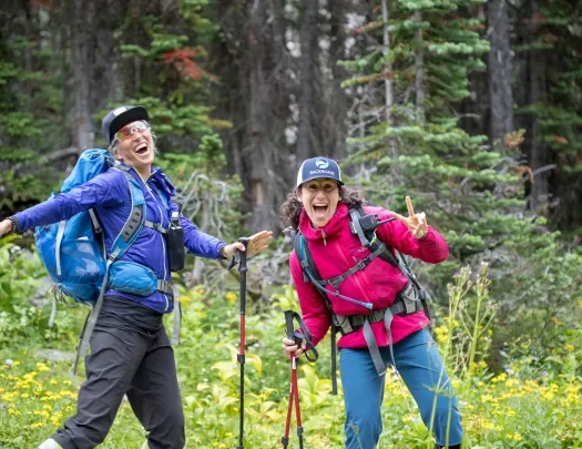 Two guests in hiking gear, posing for camera among forest.
