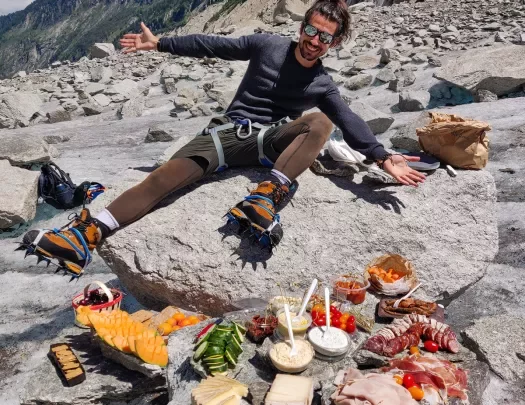 Leader overlooking lunch spread on rocks, cliffside behind them.