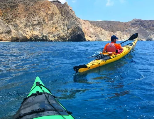 POV shot of guests kayaking, sharp cliffs in distance.
