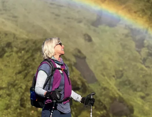 Hiker standing underneath a rainbow.